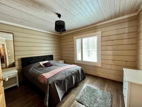 a bedroom with a bed in a room with wooden walls at Villa Wilhelmiina,LaatuLomat in Juva
