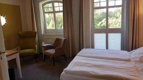 a hotel room with a bed and a desk and two windows at Ringhotel Villa Margarete in Waren