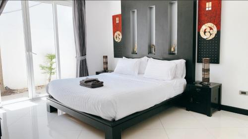 a bedroom with a large bed in a room with windows at The Palm Villa Jomtien C7 in Jomtien Beach