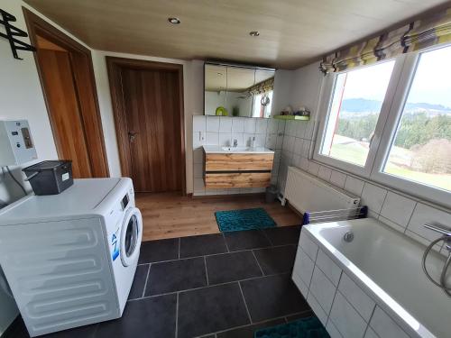a bathroom with a washing machine and a tub at Ferienwohnung Waldfrieden in Scheidegg