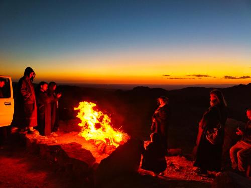 a group of people standing around a fire at sunset at Petra Desert Dream Hotel in Wadi Musa