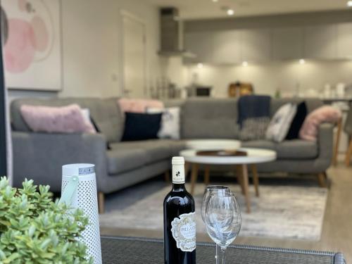 Una botella de vino sentada en una mesa con una copa de vino en 4 Putsborough - Luxury Apartment at Byron Woolacombe, only 4 minute walk to Woolacombe Beach!, en Woolacombe