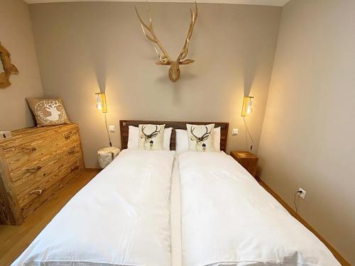 a bedroom with a white bed with antlers on the wall at Alpenstil, 4 Pax, zentral, 1 Parkplatz - RE31 in St. Moritz