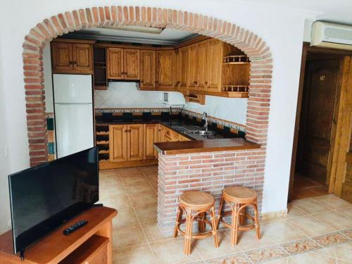 a kitchen with a brick wall and a kitchen with stools at Apartamentos Balcon de Carabeo in Nerja