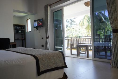 a bedroom with a bed and a balcony with a sliding glass door at Amaluna Resorts in Negombo