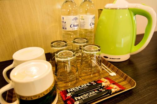 a wooden table with a tray of glasses and a jug at At Ease Hotel Suvarnabhumi in Bang Phli