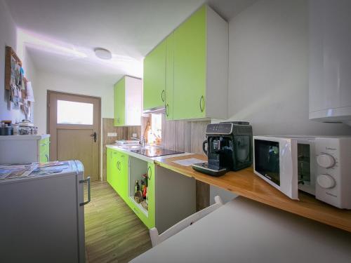 a kitchen with green cabinets and a counter with a microwave at PUŽMAN Farm Glamping in Radovljica