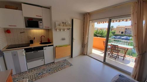 une petite cuisine avec vue sur un balcon dans l'établissement MALDIVES Joli T2 cabine proche plage Richelieu Cap d'Agde, au Cap d'Agde