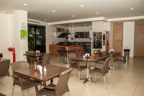 a restaurant with tables and chairs and a kitchen at Hotel Valle de San Nicolas in Rionegro