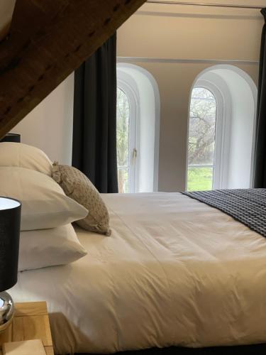 a bedroom with a large white bed with two windows at Caemorgan Mansion in Cardigan