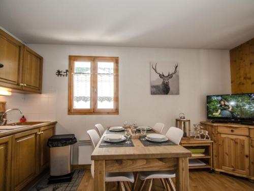 une cuisine avec une table et des chaises blanches ainsi qu'une télévision dans l'établissement Chalet calme à Chamonix, proche centre-ville avec balcons, parking et Wi-Fi - FR-1-343-212, à Chamonix-Mont-Blanc