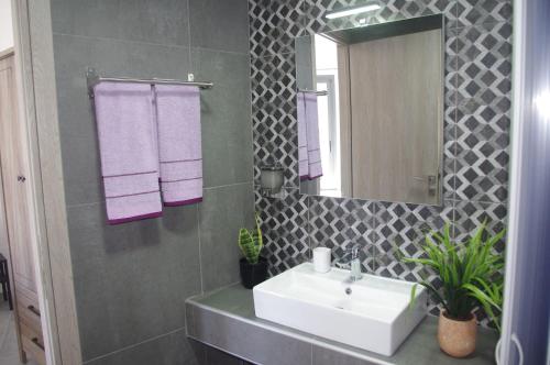 a bathroom with a sink and a mirror and purple towels at Irene Luxury Apartments in Myrtos