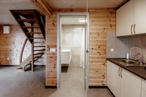 a kitchen with wooden walls and a spiral staircase at Sudecki Domek in Kudowa-Zdrój