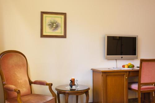 a room with a tv and a chair and a table at Hotel St. Georg in Zell am See