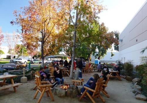 a group of people sitting in chairs around a fire at Two Bedroom - King in Master Heart of Downtown Vista in Vista
