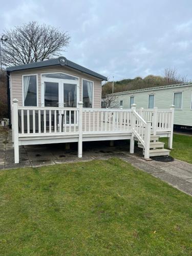 a house with a large white porch and a house at 3 Bed Platinum Caravan PRESTHAVEN SANDS in Prestatyn