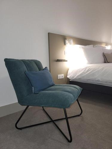a green chair in a room with a bed at Mage hôtels - HÔTEL LA GRENETTE in Roanne