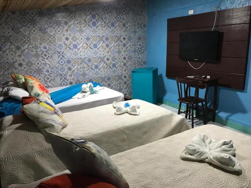 a hotel room with two beds and a television at Pousada Alto Astral in Olinda