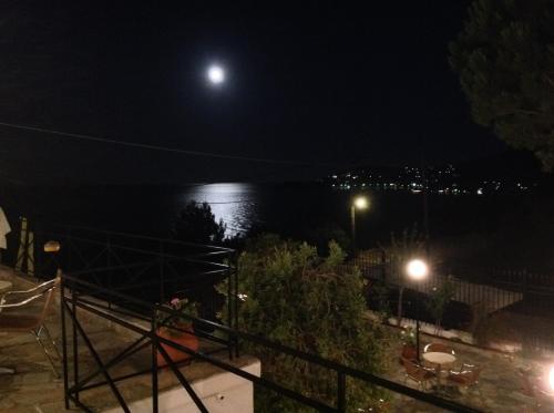 a full moon over the water at night at Travlos Studios in Póros Kefalonias