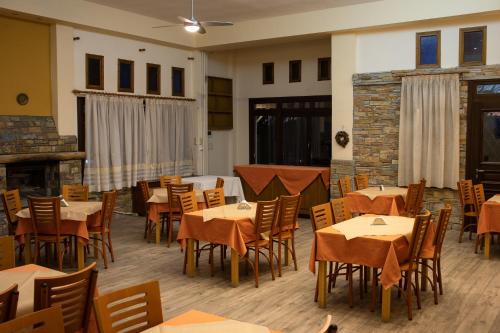 a dining room with tables and chairs and a fireplace at Hotel Defkalion in Álli Meriá