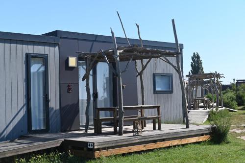 a small house with a bench on a deck at Camping Les Bois Flottés in Salin-de-Giraud