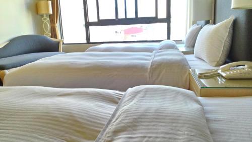 a row of white beds in a hotel room at Hotel Modern Puli in Puli