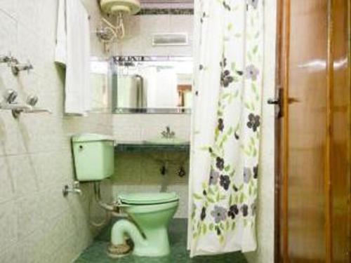 a bathroom with a toilet and a shower curtain at Hotel Woodland Deluxe in New Delhi