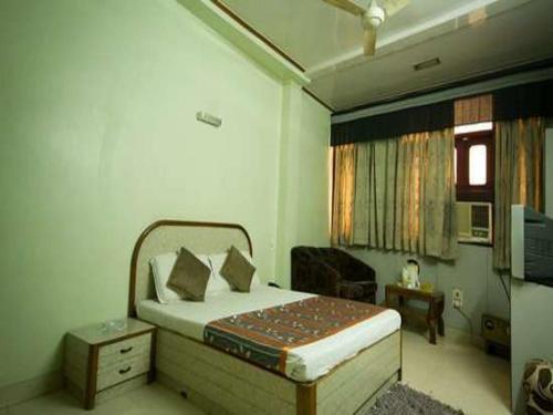 a bedroom with a bed and a television in it at Hotel Woodland Deluxe in New Delhi