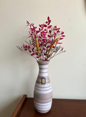 a white vase with flowers in it on a table at Casa da Fonte - Vintage House and Rooftop in Figueira da Foz