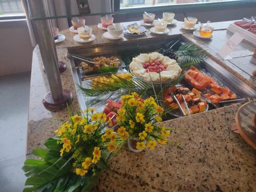 ein Buffet mit Speisen auf einem Tisch mit Blumen in der Unterkunft HOTEL MICHELS in Candelária