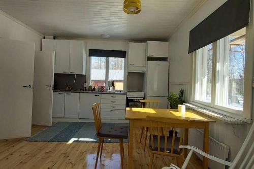 a kitchen with white cabinets and a wooden table and chairs at Villa Mäntysaari luonnonrauhaa kaupungin lähellä. in Kontiolahti