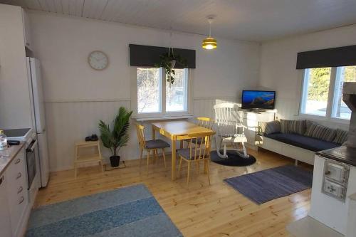 eine Küche und ein Wohnzimmer mit einem Tisch und einem Sofa in der Unterkunft Villa Mäntysaari luonnonrauhaa kaupungin lähellä. in Kontiolahti
