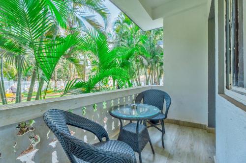 two chairs and a table on a balcony with palm trees at The Boho, Vagator Beach Goa Near Thalassa in Anjuna