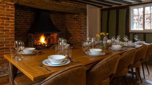a long wooden table with chairs and a fireplace at West Farm Cottage in Godmanchester