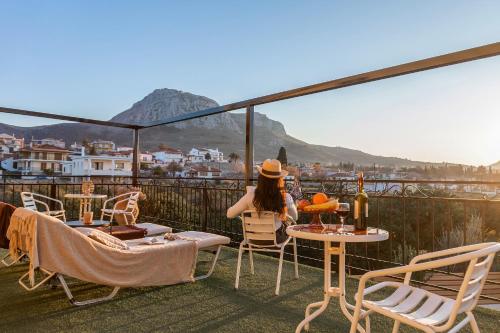 a woman sitting on a balcony looking out at the city at Jo Marinis Rooms in Korinthos