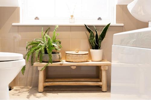 a bathroom with plants on a table next to a toilet at Elegant Apartment on Historic Cobbled High St Shrewsbury Town Centre in Shrewsbury