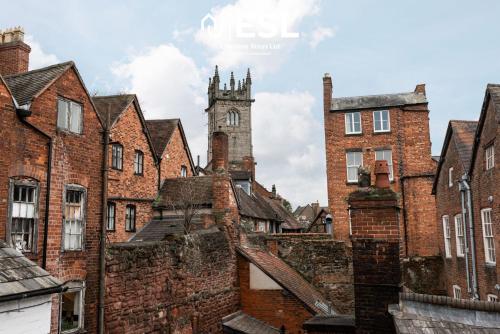 a group of brick buildings with a clock tower at Elegant Apartment on Historic Cobbled High St Shrewsbury Town Centre in Shrewsbury
