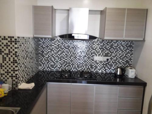 a kitchen with white cabinets and black and white tiles at Lovers Island homestay in Batu Ferringhi