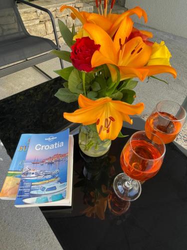 a table with a vase of flowers and a book at Apartment Jukic in Sveti Filip i Jakov