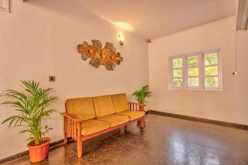 a living room with a couch and two plants at The Boho, Vagator Beach Goa Near Thalassa in Anjuna