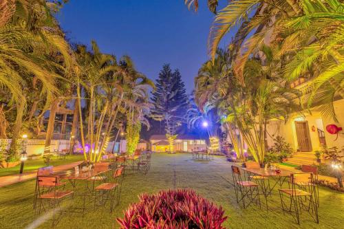 a group of tables and chairs in a courtyard with palm trees at The Boho, Vagator Beach Goa Near Thalassa in Anjuna