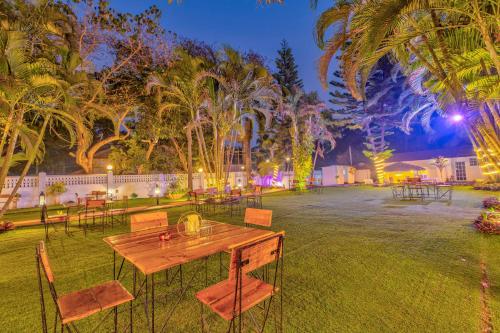 a wooden table and chairs in a yard with palm trees at The Boho, Vagator Beach Goa Near Thalassa in Anjuna