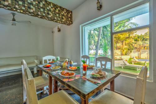 a dining room with a table and chairs and a window at The Boho, Vagator Beach Goa Near Thalassa in Anjuna