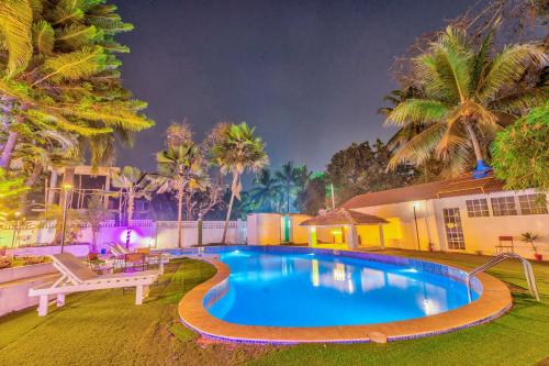 uma piscina em frente a uma casa com palmeiras em The Boho, Vagator Beach Goa Near Thalassa em Anjuna