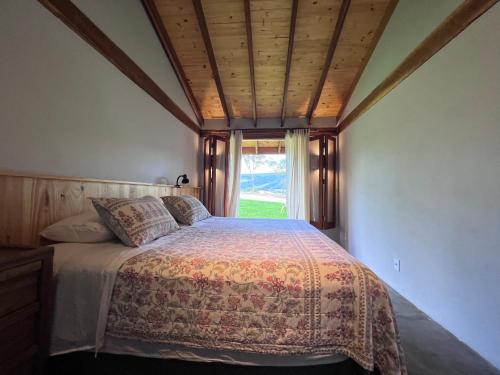 1 dormitorio con 1 cama y ventana grande en Refúgio Morro Alto, en Delfinópolis