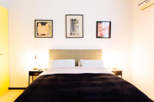 een slaapkamer met een bed en drie foto's aan de muur bij House in Shalma in Tel Aviv