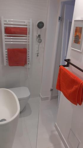 Baño blanco con aseo y toallas de color naranja en Maison Ilaguinabaita 255 bis en Urrugne