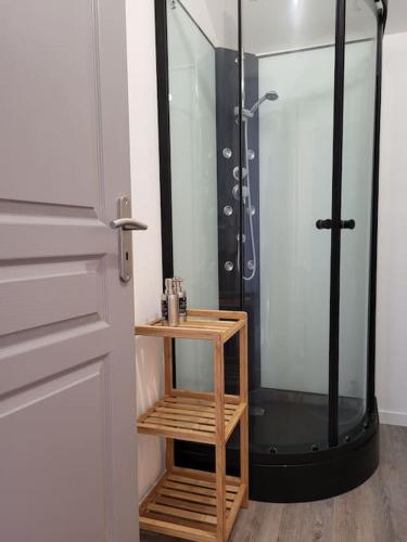 une douche avec une porte en verre à côté d'une étagère en bois dans l'établissement appartement proche des remparts, à Langres