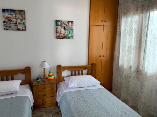a bedroom with two beds and a dresser and a window at Panormo House in Panormos Rethymno