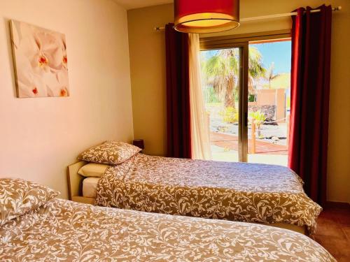 a bedroom with two beds and a window with a view at Villa Irina in Caleta De Fuste